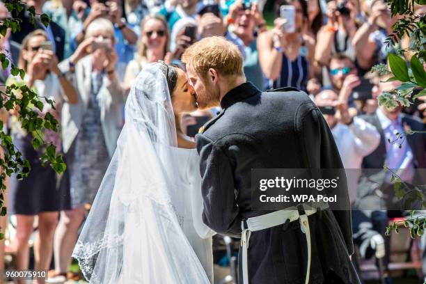 Prince Harry, Duke of Sussex and The Duchess of Sussex kiss on the steps of St George's Chapel in Windsor Castle after their wedding on May 19, 2018...