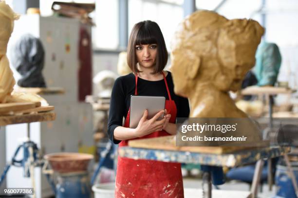 young female sculptor sta lavorando con il tablet digitale nel suo studio - baranozdemir foto e immagini stock