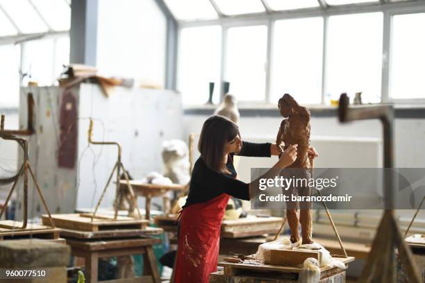 jonge vrouwelijke beeldhouwer werkt in haar atelier - ceramic stockfoto's en -beelden