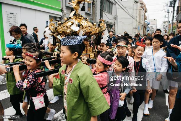 Japanese children wearing &quot;happi&quot; coats carry a portable shrine or &quot;mikoshi&quot; through the streets of Asakusa during Tokyo's one of...