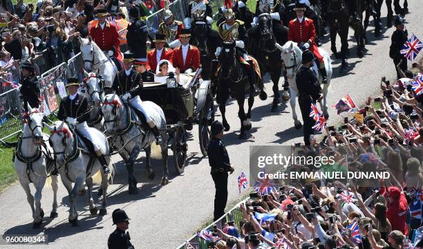 Britain's Prince Harry, Duke of Sussex and his wife Meghan, Duchess of Sussex wave from the Ascot Landau Carriage during their carriage procession on...