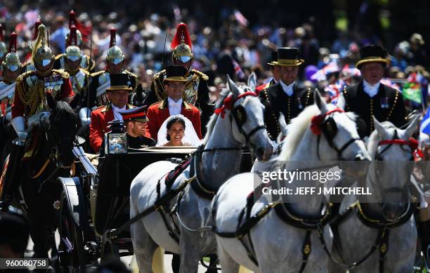 Britain's Prince Harry, Duke of Sussex and his wife Meghan, Duchess of Sussex wave from the Ascot Landau Carriage during their carriage procession on...