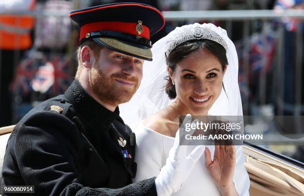 Britain's Prince Harry, Duke of Sussex and his wife Meghan, Duchess of Sussex wave from the Ascot Landau Carriage during their carriage procession on...