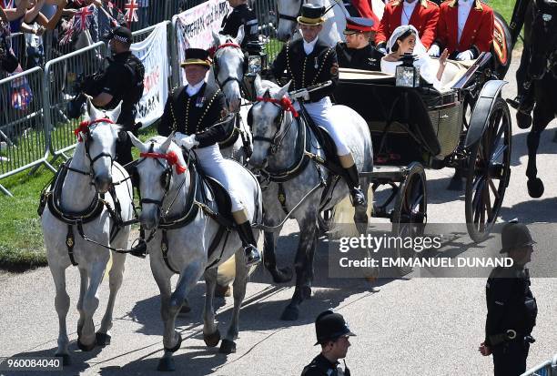 Britain's Prince Harry, Duke of Sussex and his wife Meghan, Duchess of Sussex wave from the Ascot Landau Carriage during their carriage procession on...