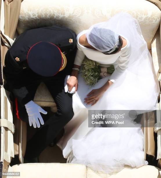 Prince Harry, Duke of Sussex and the Duchess of Sussex hold hands in the Ascot Landau Carriage as their carriage procession rides along the Long...