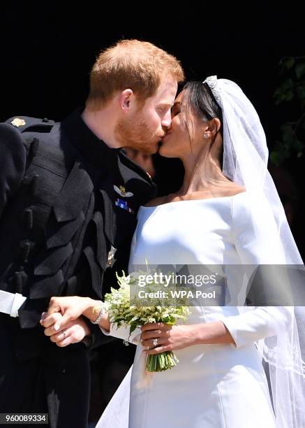 Britain's Prince Harry, Duke of Sussex kisses his wife Meghan, Duchess of Sussex as they leave from the West Door of St George's Chapel, Windsor...