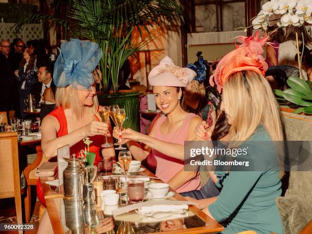 Attendees wear decorative hats and raise a champagne toast during a royal wedding viewing party at the Plaza Hotel in New York, U.S., on Saturday,...