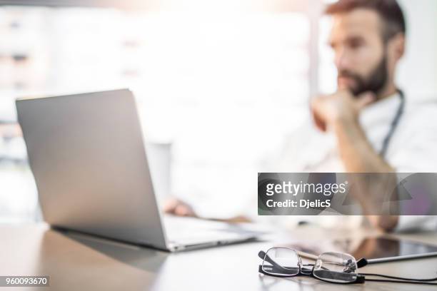 busy doctor's desk. - doctor using laptop stock pictures, royalty-free photos & images