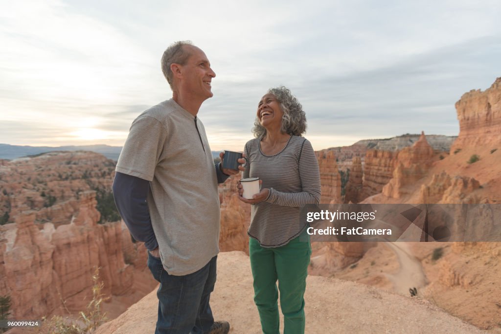 Um casal sênior em um café de bebida de caminhada no deserto juntos ao nascer do sol