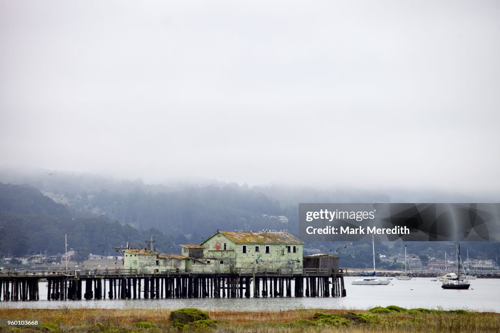 Old pier and buildings on a foggy day at Half Moon Bay