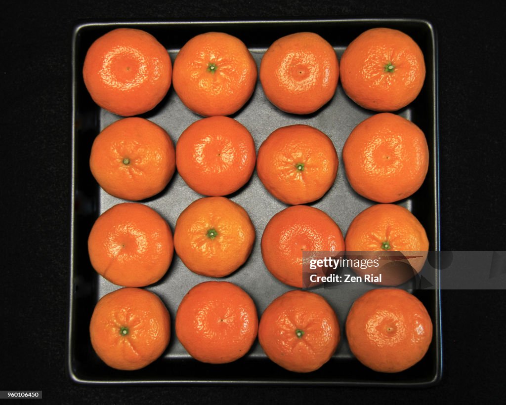 Mandarine orange (citrus reticulata) fruits arranged side by side on black tray