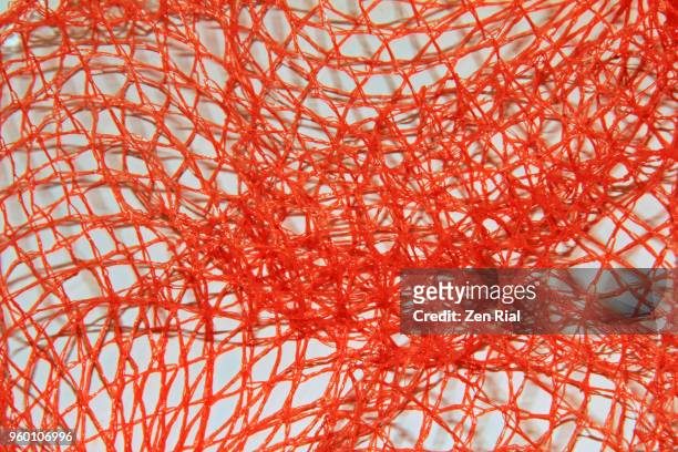 disposable orange plastic mesh produce bag on white background - rede têxtil imagens e fotografias de stock