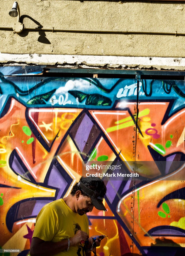 Man using texting on a mobile phone by a Venice Beach mural