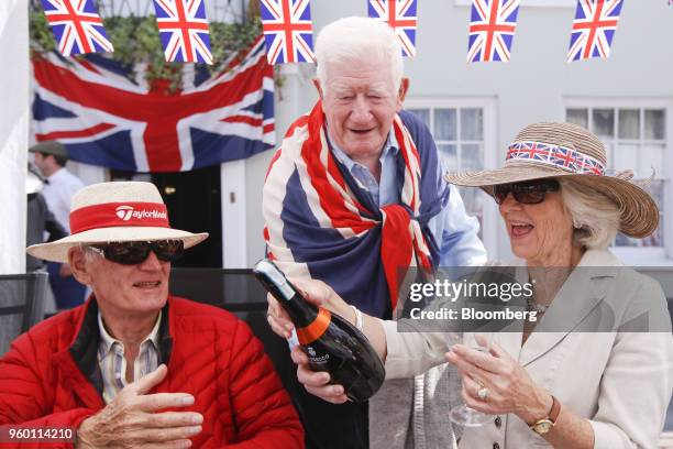 Attendees prepare to open a bottle of sparkling wine as they sit under Union flag, also known as Union Jacks, bunting during a street party to...