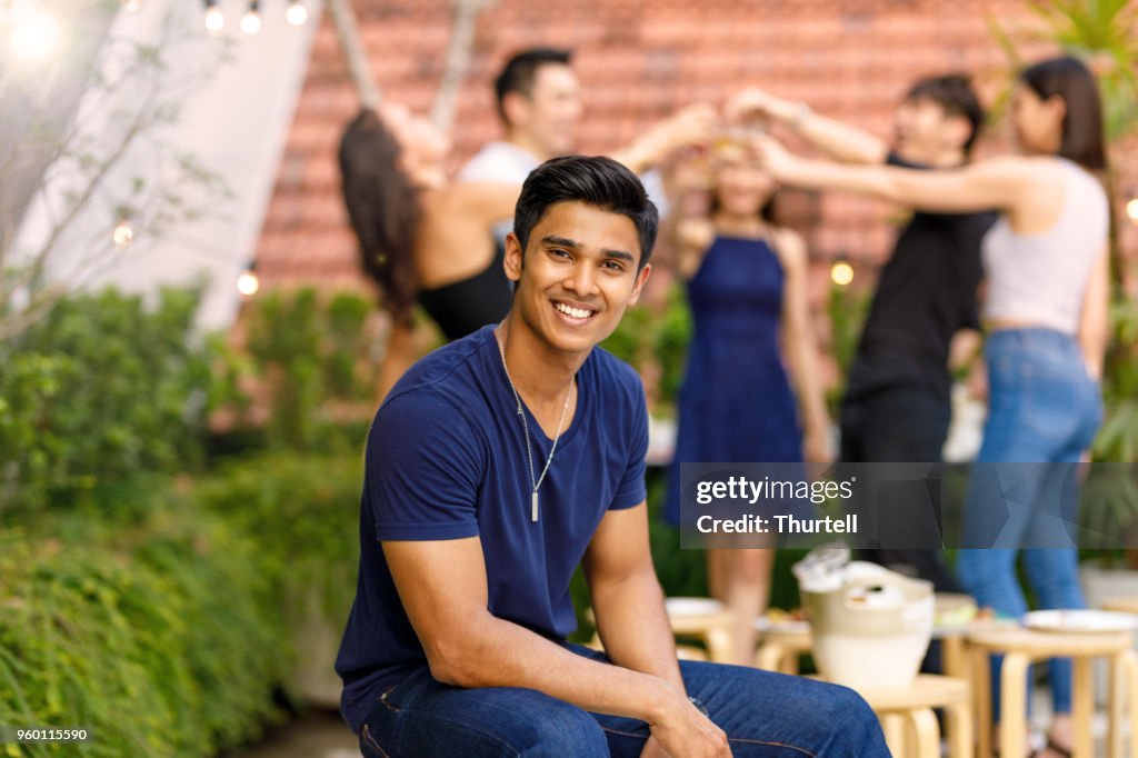Young Asian Man Enjoying Outdoor Roof Top Party With Friends