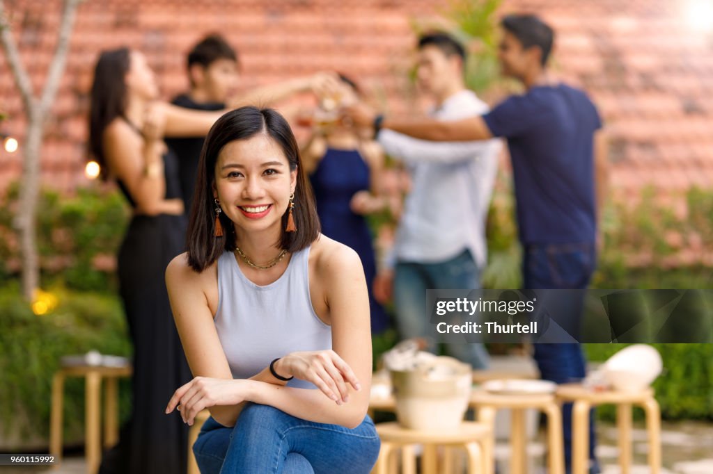 Portrait Of Young Asian Woman At Outdoor Roof Top Party With Friends