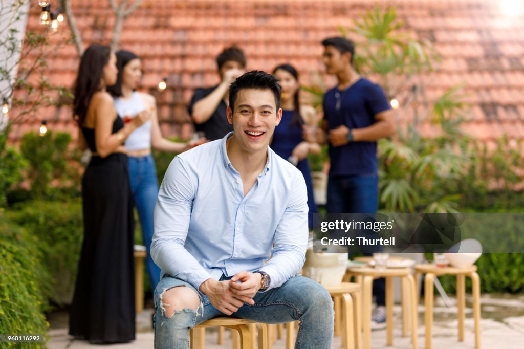 Young Asian Man Enjoying Outdoor Roof Top Party With Friends