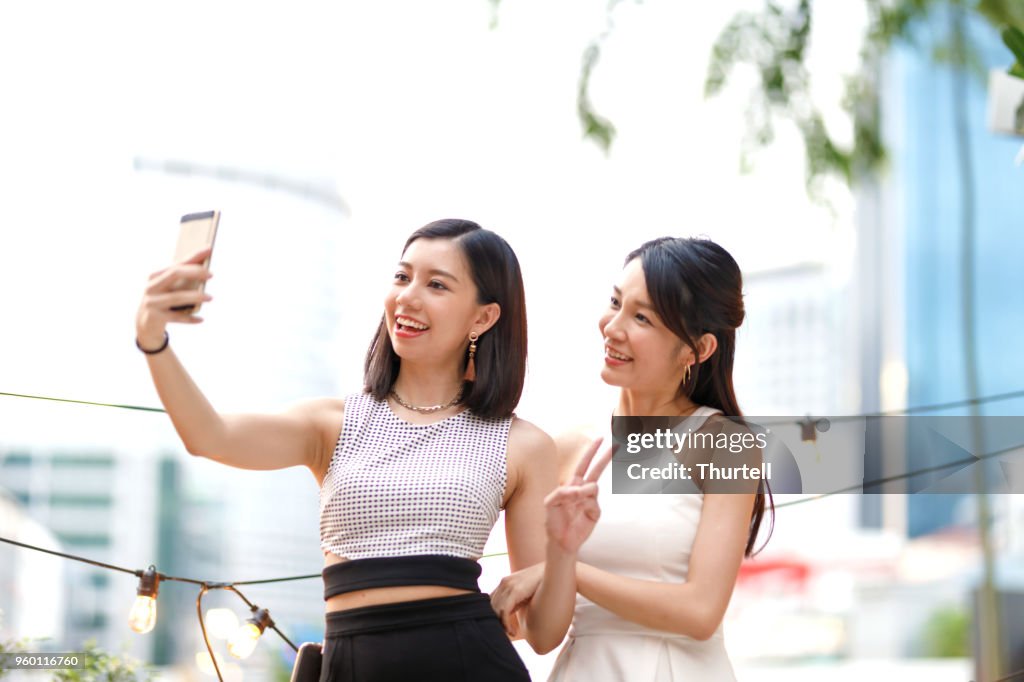 Amigas asiáticas tomar autorretratos en azotea al aire libre superior partido