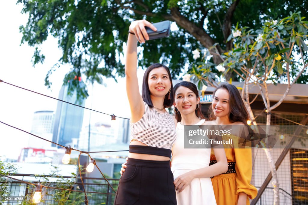 Femininos amigos asiáticos, tendo Selfies no telhado exterior Top festa