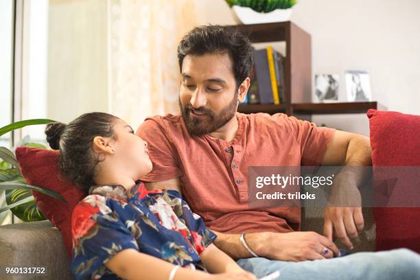 father with daughter relaxing on sofa - asian father and daughter stock pictures, royalty-free photos & images