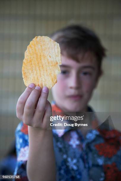 boy holding potato chip - doug byrnes stock-fotos und bilder