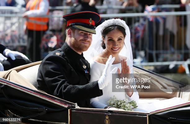 Prince Harry, Duke of Sussex and Meghan, Duchess of Sussex wave from the Ascot Landau Carriage during their carriage procession on Castle Hill...