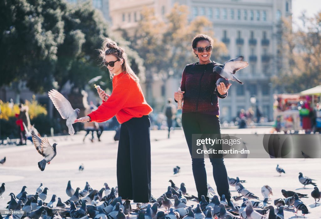 Women traveling in Europe and feeding pigeons in Barcelona