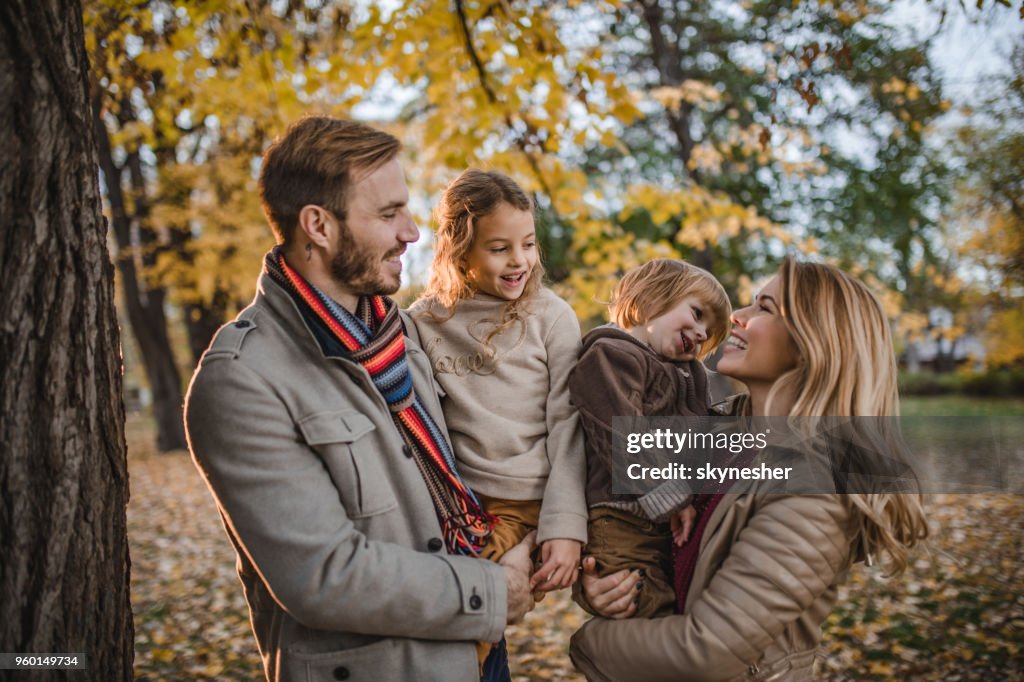 Young happy family communicating while enjoying in autumn day at the park.