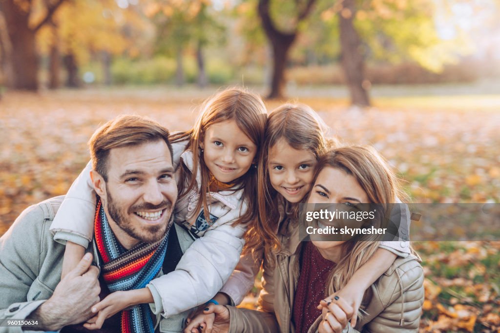 Happy parents and their small daughter in autumn day.