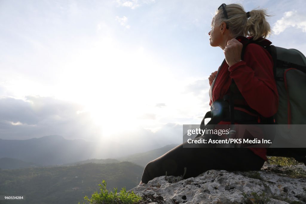 Female hiker relaxes on ridge crest above distant hills