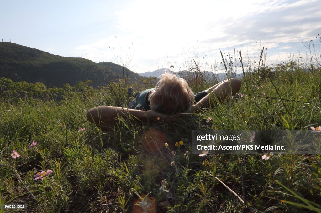 Male hiker relaxes in meadow above distant hills