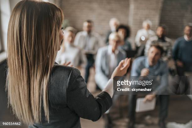 female manager talking to large group of her colleagues on a business seminar. - speech stock pictures, royalty-free photos & images