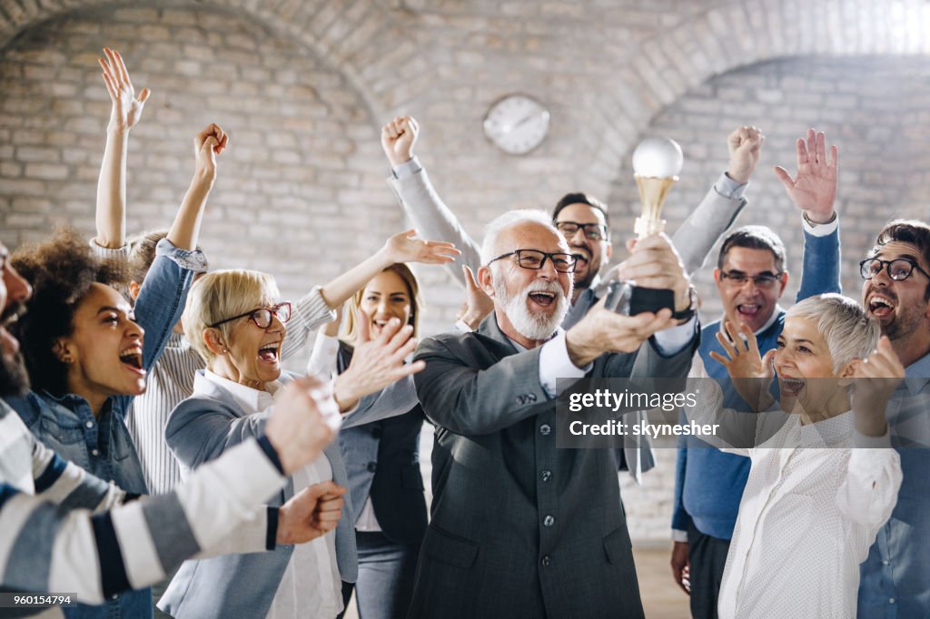 Grote groep van vrolijke zakenmensen met een trofee in het kantoor.