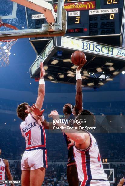 Truck Robinson of the New York Knicks shoots over Kelly Tripucka and Bill Laimbeer of the Detroit Pistons during an NBA basketball game circa 1984 at...