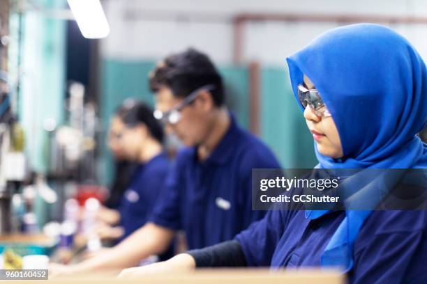 hijabi vrouw die werkt in een team met andere werknemers van de fabriek te voltooien van het verpakkingsproces - india lab stockfoto's en -beelden