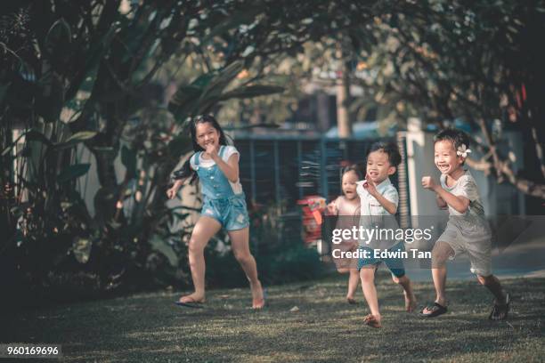 asian chinese family having fun bonding time in front of their house where children running towards parents