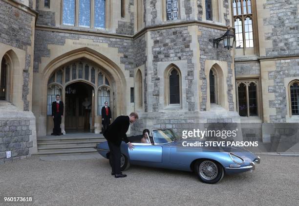 Britain's Prince Harry, Duke of Sussex, opens the passenger door of an E-Type Jaguar car for his wife Meghan Markle, Duchess of Sussex, as they leave...