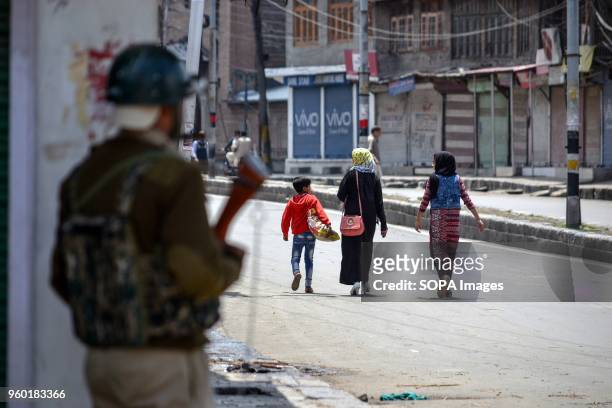 Kashmiri residents walk past Indian paramilitary troopers amid restrictions on civilian movements ahead of Indian PM Narendra Modi's visit in...