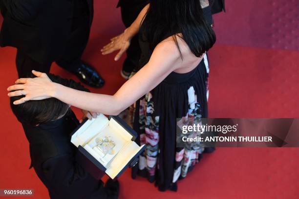 Lebanese director and actress Nadine Labaki taps the head of Syrian actor Zain al-Rafeea, who hods Labaki's Jury Prize award, on May 19, 2018...
