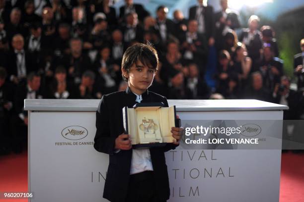 Syrian actor Zain al-Rafeea poses with the trophy on May 19, 2018 during a photocall after Lebanese director and actress Nadine Labaki won the Jury...