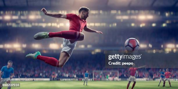 soccer player in mid air volley ball during football match - soccor games stock pictures, royalty-free photos & images