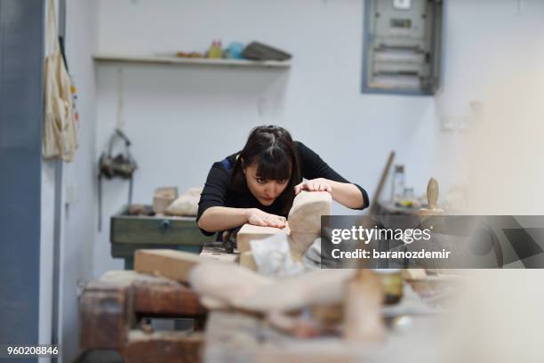 jeune femme sculpteur travaille dans son atelier - couteau à découper photos et images de collection