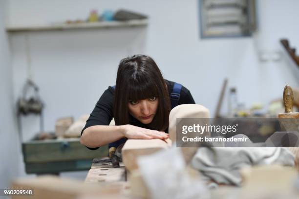 jovem escultor feminino está trabalhando em seu estúdio - carving knife - fotografias e filmes do acervo