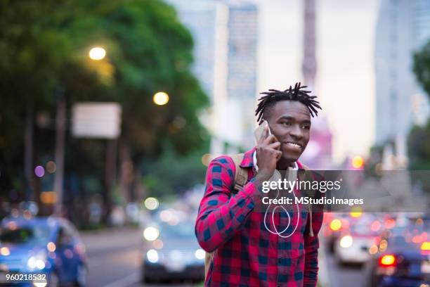 lächelnder afrikanischen mann am telefon zu sprechen. - nigeria city stock-fotos und bilder
