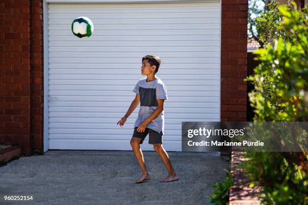 young boy kicking football on driveway - football australien stock pictures, royalty-free photos & images