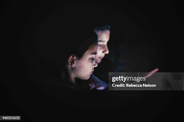 set of boy and girl twins using digital tablets in dark room at night - digital twin bildbanksfoton och bilder