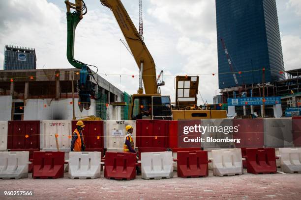 Workers walk past The Exchange 106 under construction, right, in the Tun Razak Exchange financial district of Kuala Lumpur, Malaysia, on Saturday,...