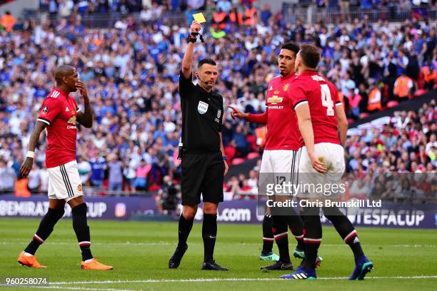 Referee Michael Oliver shows Phil Jones of Manchester United a yellow card after a foul in the penalty area during the Emirates FA Cup Final between...