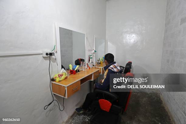 An adolescent boy sits in a chair in front of a mirror where he is learning hairdressing skills at the "Hori" rehabilitation centre for former...