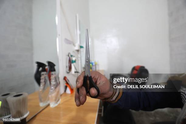 An adolescent boy holds scissors as he learns hairdressing skills at the "Hori" rehabilitation centre for former Islamic State group child fighters...